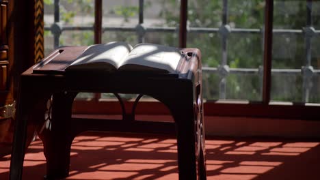 libro abierto en una pequeña mesa junto a una ventana