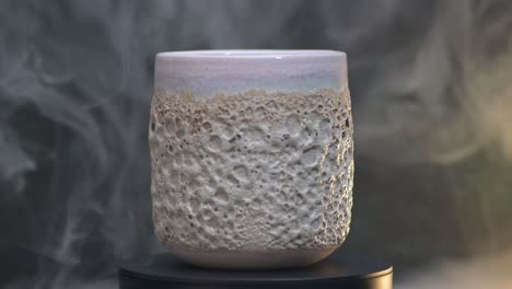 primer plano de un vidrio de cerámica con textura de coral girando alrededor de su eje en el humo