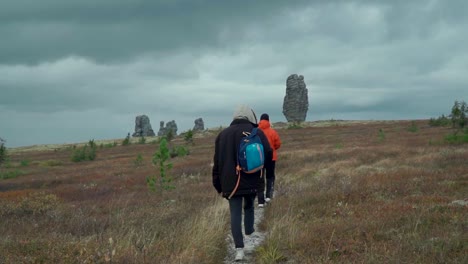 hikers on a trail amidst unique rock formations in the autumn