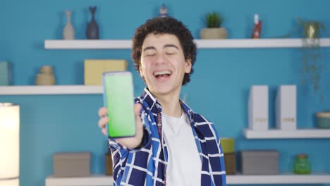 successful young man turns phone to camera. green screen.