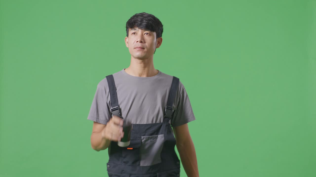 아시아인 노동자가 녹색 스크린 배경 스튜디오에서 는 동안 커피를 마시고 있습니다.