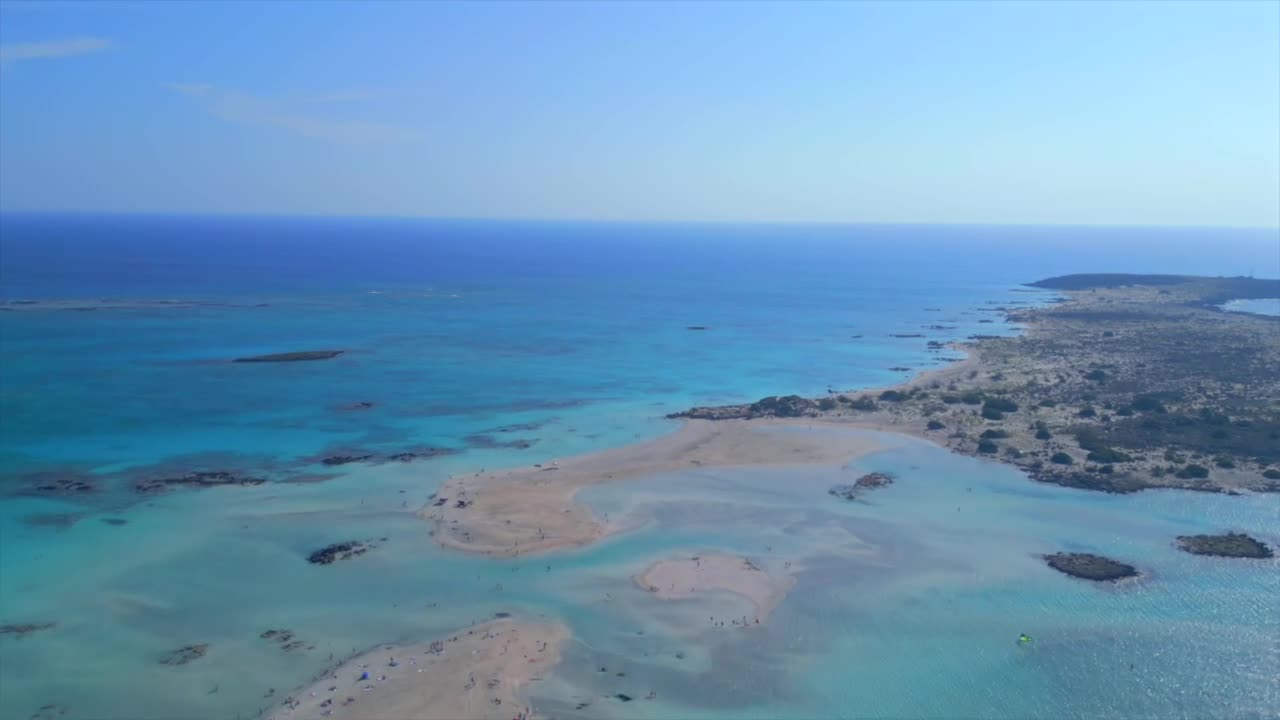 drone shot captures Elafonisi Beach in Crete, Greece. The footage showcases the sandbar connecting Crete to Elafonisi, surrounded by turquoise waters. Ideal for travel and nature projects