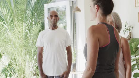 ancianos felices y diversos hablando con una entrenadora de pilates en una habitación soleada, sin alteración, en cámara lenta