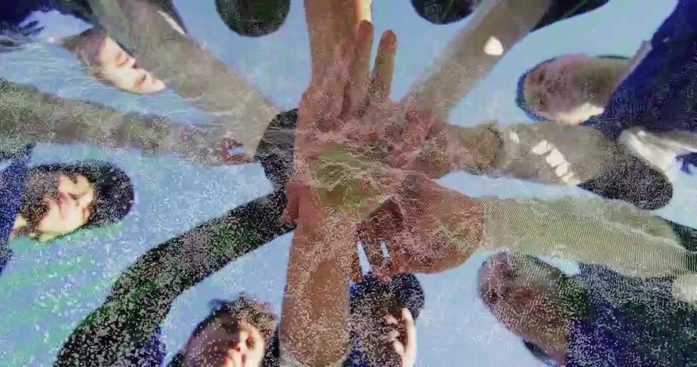 Ground cam capturing eight athletes in baseball caps pregame huddling and stacking hands for unity
