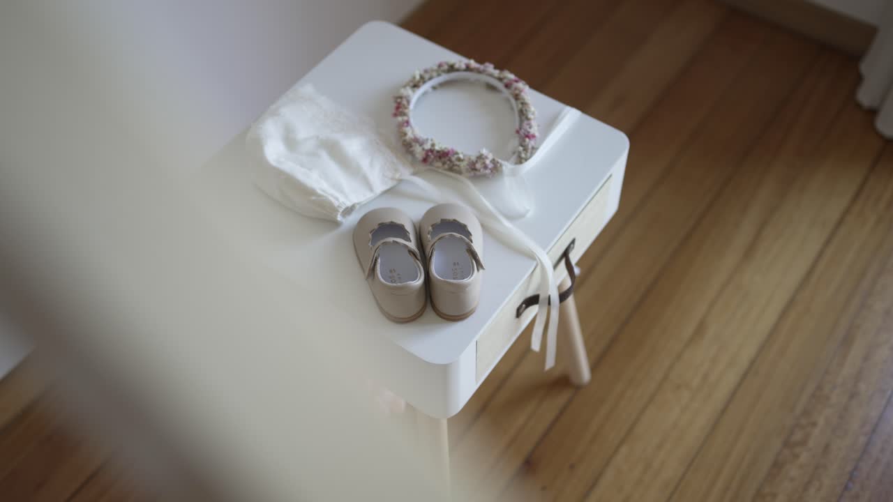 Infant shoes bonnet and floral headband placed on stool indoors
