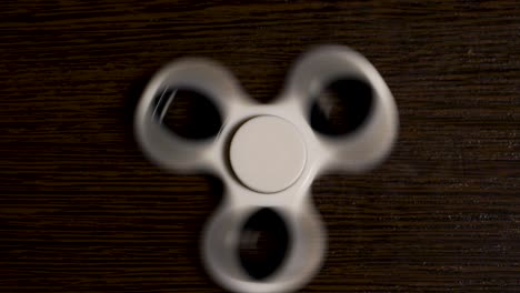 white fidget spinner spinning on a dark wooden table