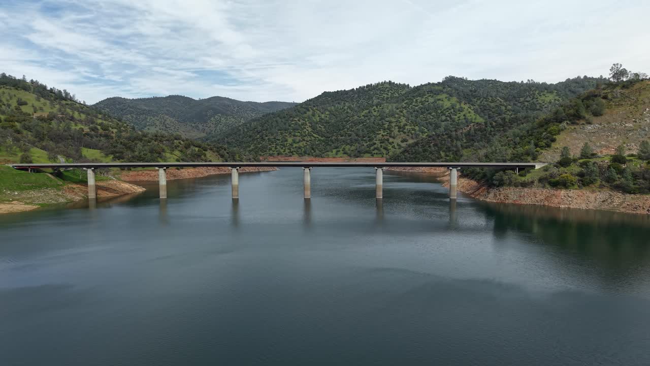 A sweeping aerial view highlights the Don Pedro Reservoir Bridge as it cuts through the serene waters below. Shot on a DJI Air 3S.