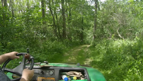 View-of-hands-and-steering-wheel-of-a-man-driving-a-UTV-pm-a-grassy-trail-through-the-woods
