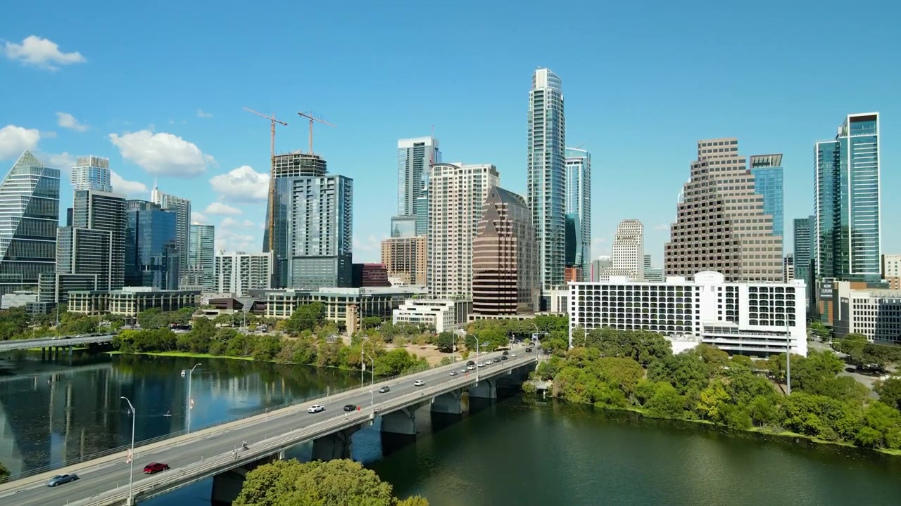 Voo de drone aéreo sobre o centro da cidade de Austin, Texas, tráfego na ponte da Congress Avenue, arranha-céus, Parque Urbano e o Rio Colorado refletindo edifícios altos americanos.