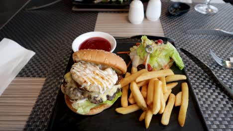 una deliciosa hamburguesa y papas fritas servidas en un hermoso plato de pizarra negra