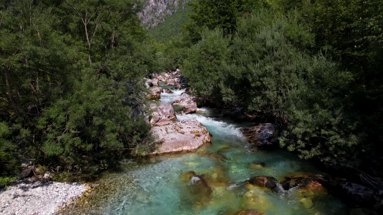 agua esmeralda limpia del río valbona en albania, fluyendo y espumeando a través de acantilados y árboles verdes