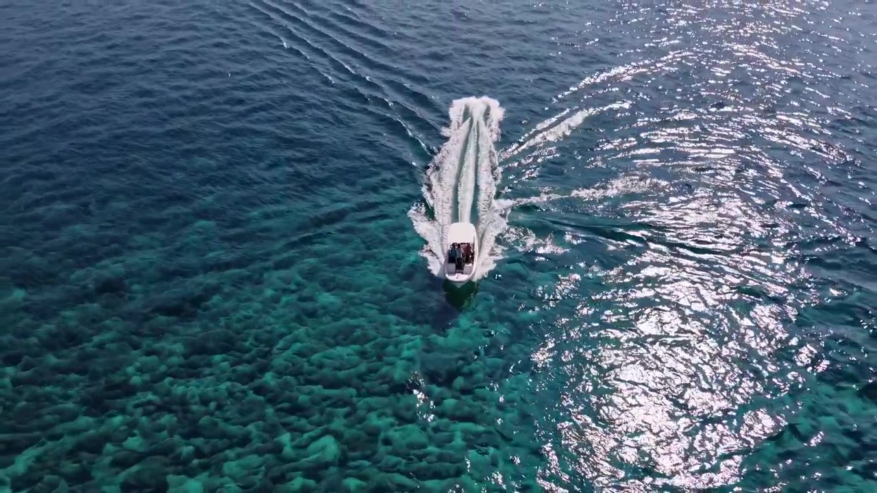 Vista aerea di un motoscafo che naviga su acqua oceanica limpida e turchese