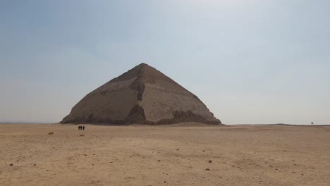 Blick-Auf-Die-Alte-Gebogene-Sneferu-Pyramide-In-Dashur,-Menschen-Gehen-An-Der-Pyramide-Vorbei