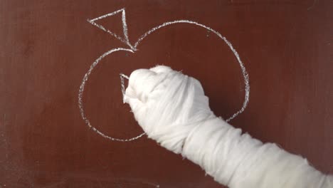 textured brown chalkboard background mummy's hand in bandages writing 'mummy' on the board with a