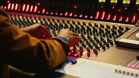 Audio-technician-producing-new-music-at-mixing-console-in-control-room