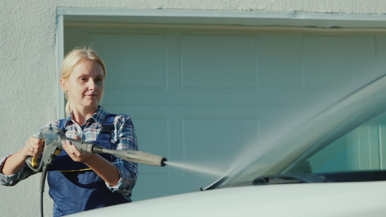 una mujer lavando mi auto en el patio trasero de su casa al fondo de las puertas del garaje