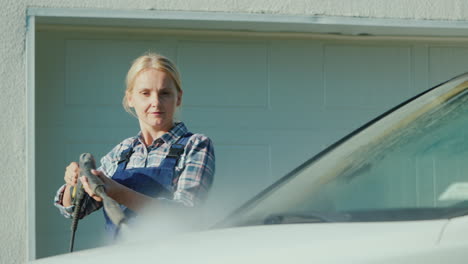 a woman washing my car in the backyard of her house on the background of the doors to the garage