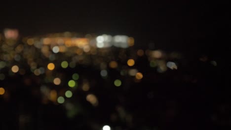 scenic wide shot panning over city lights and fireworks bokeh rack focus