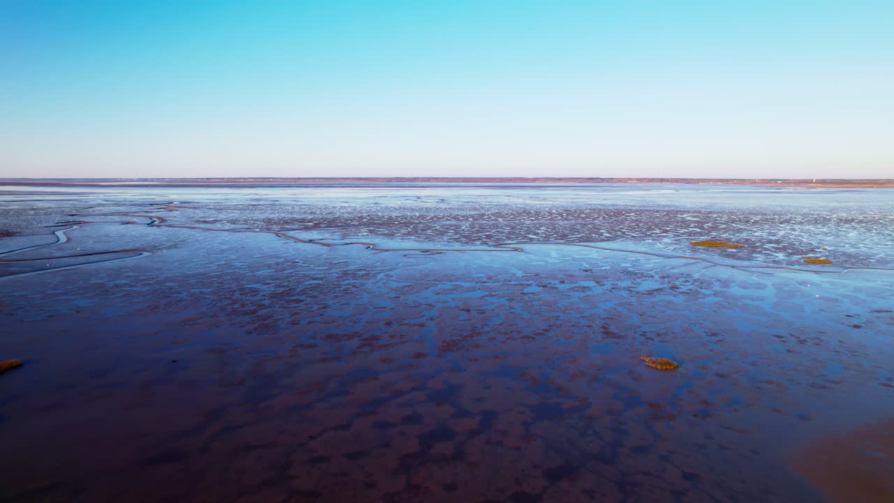 Aerial drone shot of a lake water with the view of blue sky in the background. Low water levels visible during drought season.