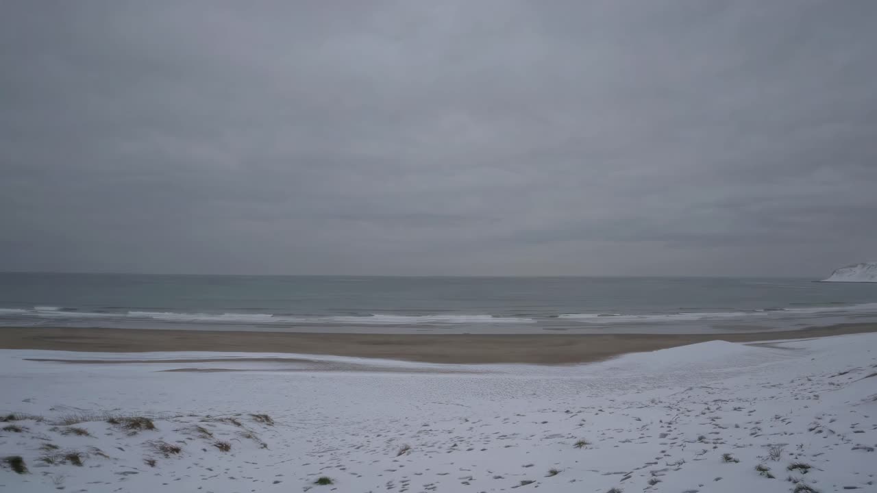 A serene video captures a snowy beach landscape from a wide-angle perspective