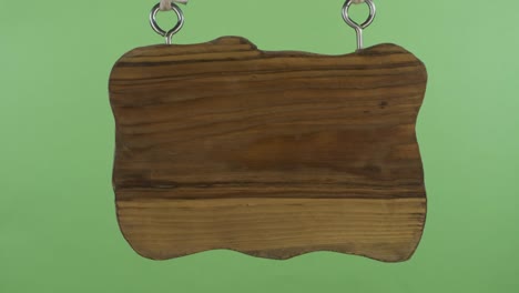 panorama di un vecchio cartello di legno appeso a una corda. isolato sullo sfondo verde