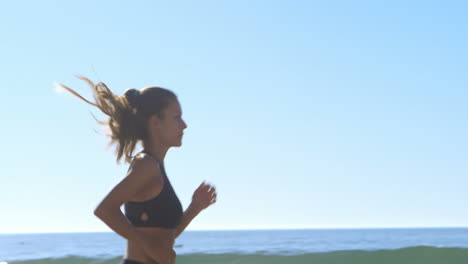 mujer en forma corriendo en la playa 4k