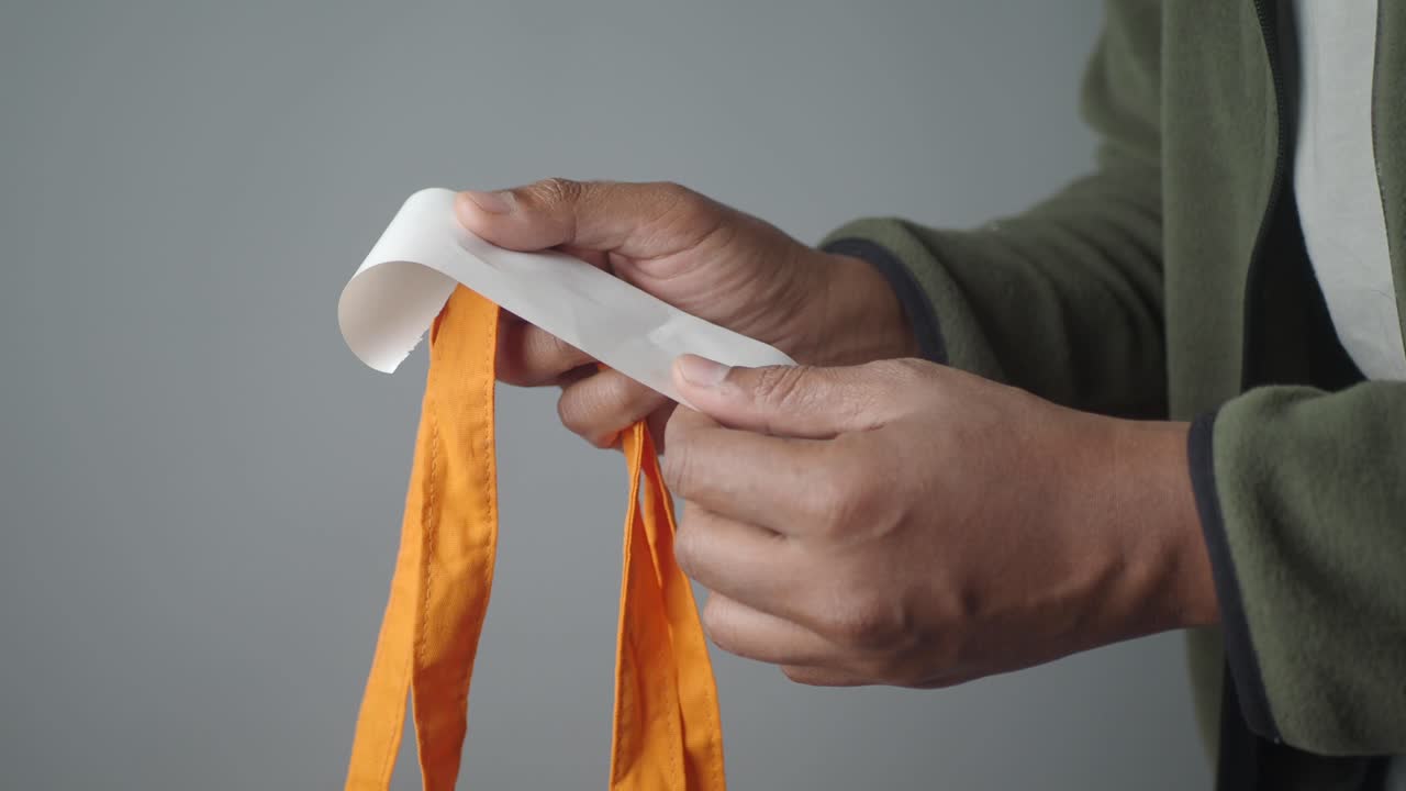 Person holding an orange bag with a white label