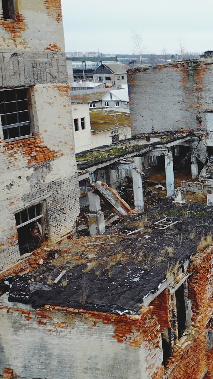 Destroyed old factory. The littered roof and walls of industrial buildings. Aerial view. Vertical video
