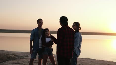 Friends-are-spending-time-together-on-the-seaside.-Talking,-smiling,-discussing-something.-Youth-culture.-Evening