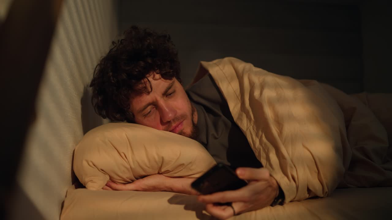 hombre durmiendo y usando el teléfono en la cama