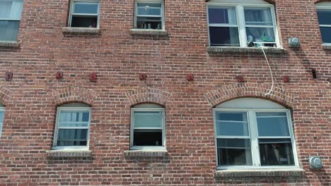 fun downward tracking drone shot of side of red brick apartment building with windows