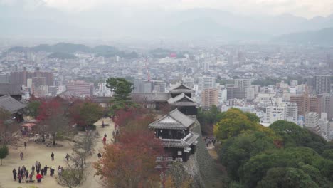 Pan-up-over-Castle-grounds-of-Matsuyama-Castle-with-city-in-distance