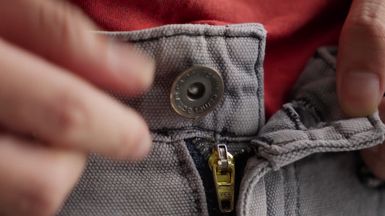 las manos desabrochan los pantalones vaqueros grises, se desnudan, estrecho estrecho