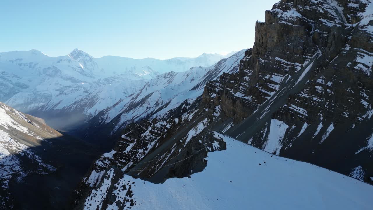 volando sobre la cima de la montaña con la bandera de oración tibetana, montañas cubiertas de nieve paisaje en la distancia, aéreo