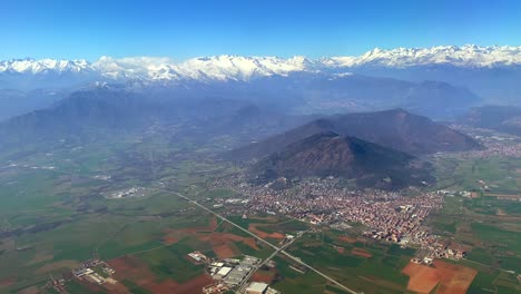 aerial footage of a green valley surmounted by mountains covered in snow