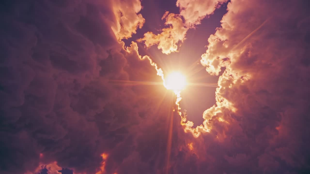 Dramatic upward angle captures the sun breaking through dark clouds, creating a cinematic, ethereal