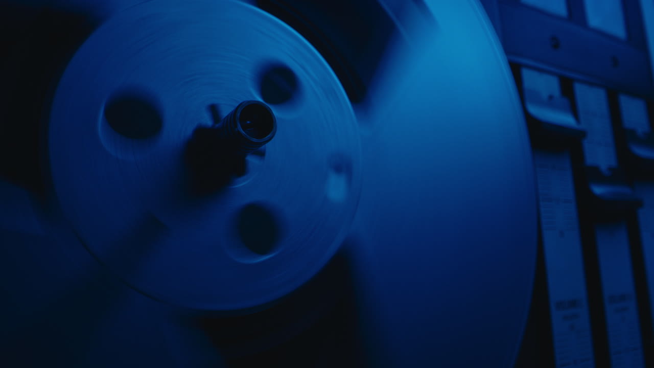 A vintage tape recorder spinning spools in a blue light