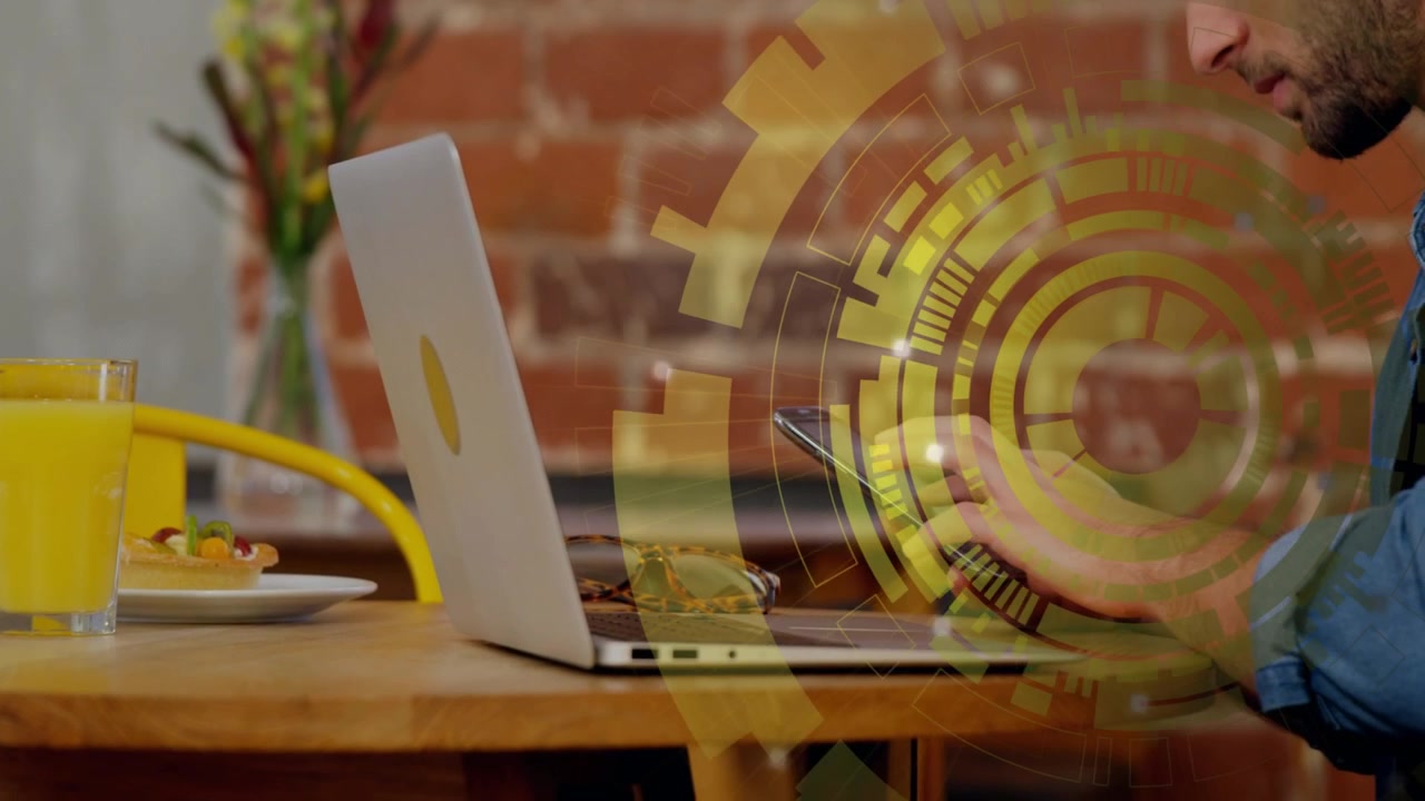 Freelancer uomo che digita sul laptop, tocca lo smartphone, attivando un HUD che si sovrappone alle mani per lavoro tecnologico.