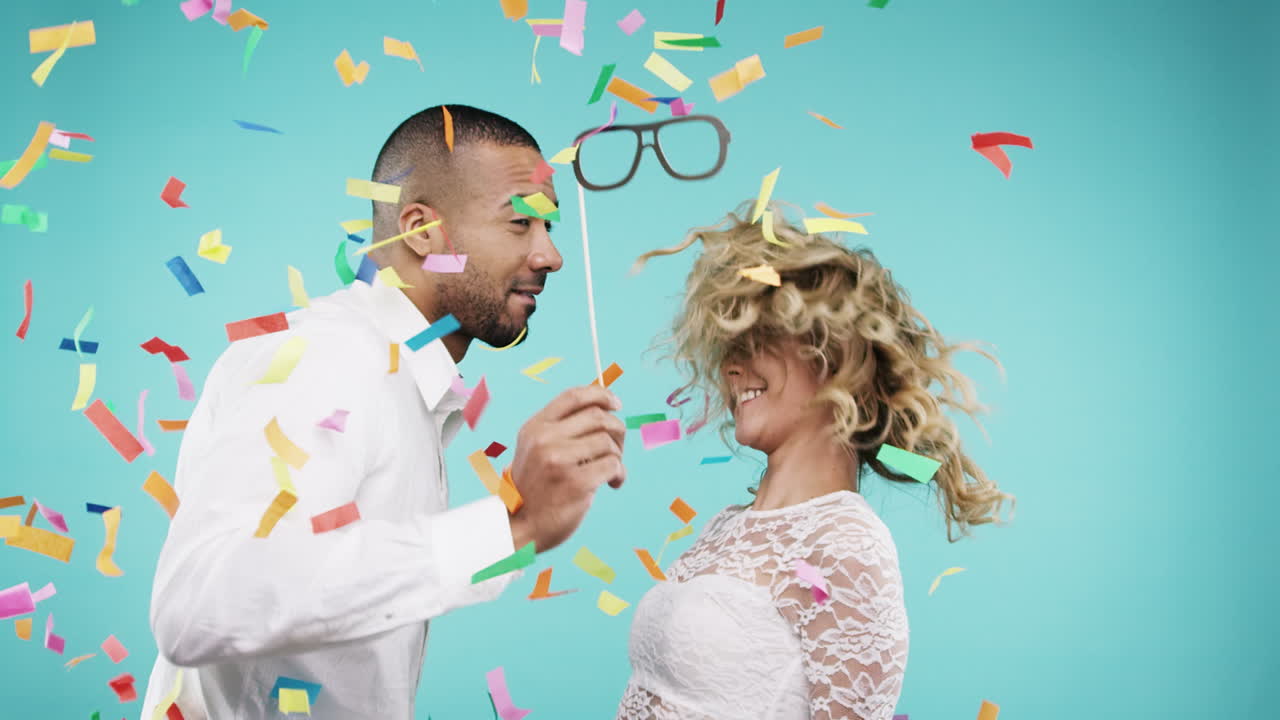 una pareja celebrando con confeti y accesorios para la cabina de fotos.