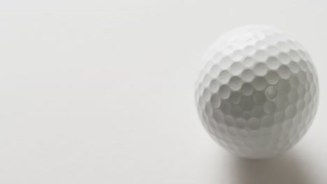 close up of golf ball on white background, copy space, slow motion