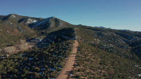 Aerial-moving-down-mountain-desert-road-with-car-parked-on-scenic-overlook