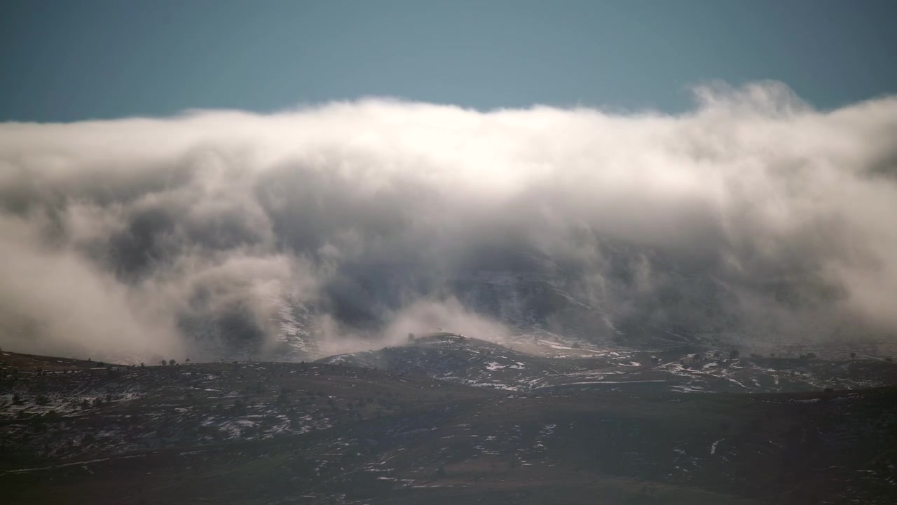 Nuages épais s'étendant sur des sommets de montagnes enneigés