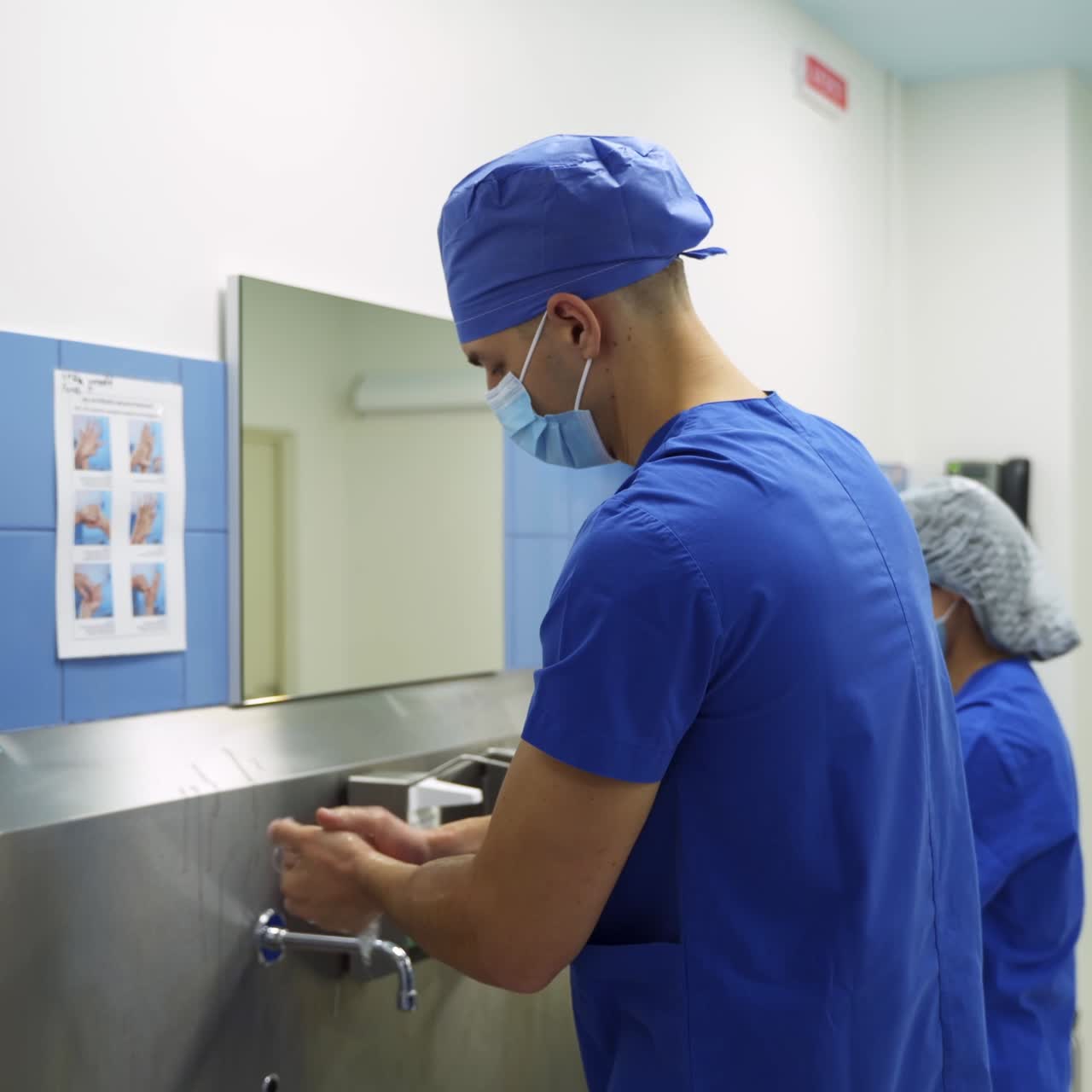 Surgeon doctors preparing carefully for operation. Male doctor washing hands with soap up to his elbows. Side view