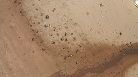 aerial flyover of a pitted sandy beach at sunset