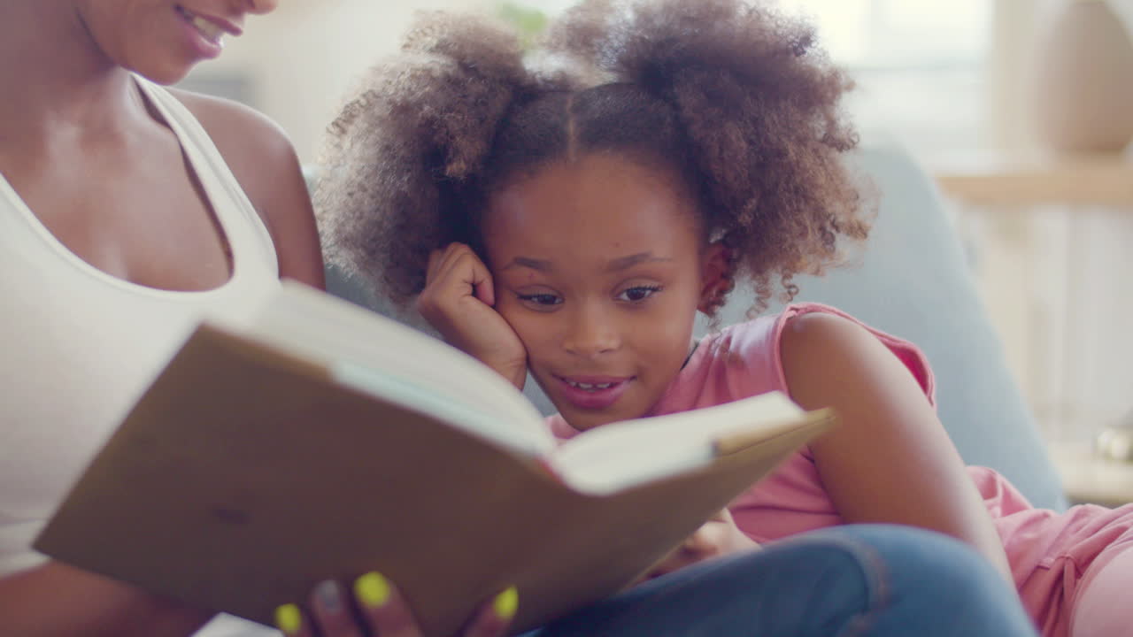 Close up of an African American woman reading fairy tales to her happy daughter