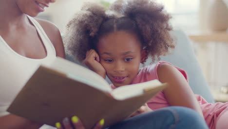 close up of an african american woman reading fairy tales to her happy daughter