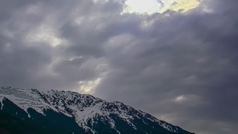 Tiefwinkelaufnahme-Dunkler-Wolken,-Die-Sich-Im-Zeitraffer-über-Den-Schneebedeckten-Berggipfel-Bewegen