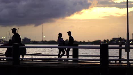 people hanging out on the docks during sunset while fishing.
