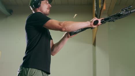 a man wearing goggles and ear protection unloads a long gun by removing the magazine clip and checking for rounds in the chamber at an indoor firing range