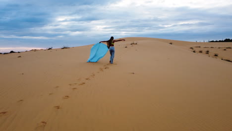 Mujer-Caminando-Por-Las-Dunas-De-Arena-Roja-Con-Material-Azul